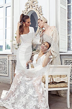 Three young pretty lady in white lace fashion style dress posing in rich interior of royal hotel room, luxury lifestyle