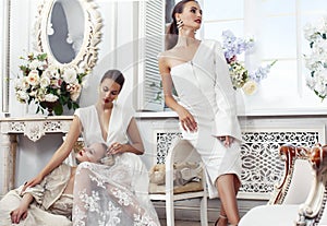 Three young pretty lady in white lace fashion style dress posing in rich interior of royal hotel room, luxury lifestyle