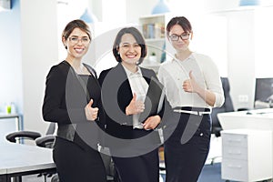 Three young successful business women in the office smiling happily