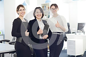 Three young successful business women in the office smiling happily