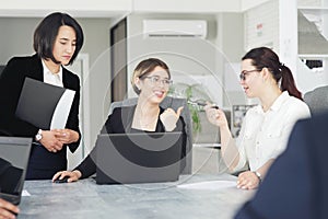 Three young successful business women in the office, together, happily working on a project