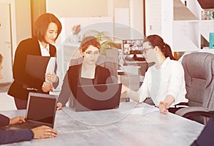 Three young successful business women in the office, together, happily working on a project