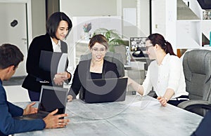 Three young successful business women in the office, together, happily working on a project