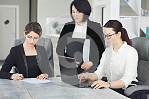 Three young successful business women in the office working together on a project