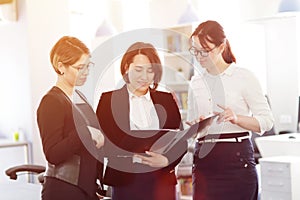 Three young successful business women in the office working together on a project