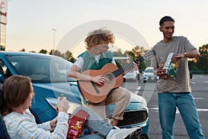 Three young well-dressed friends of different nationalities having a good time together outside on a parking site