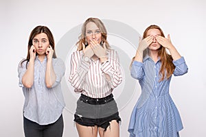 Three young woman friend posing with closing eyes ears and mouth looking at camera medium shot