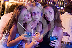 Three young women with drinks in a nightclub