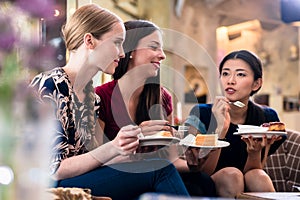 Three young women eating cake indoors
