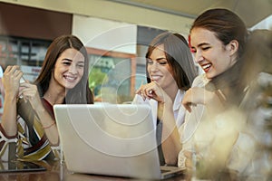 Three young women having conversation in cafe.