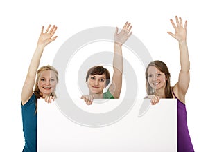 Three young women holding a banner and greeting