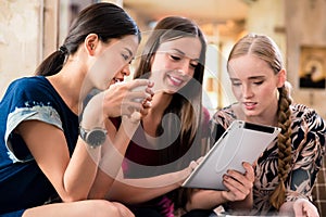 Three young women looking at pictures on tablet