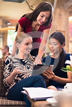 Three young women looking at pictures on tablet