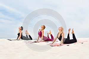 Three young women perform yoga exercises