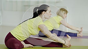 Three young women are practicing the Revolved Head-to-Knee pose