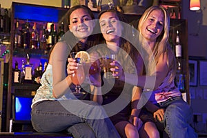 Three young women sitting on a bar counter