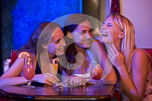 Three young women sitting at a table and laughing