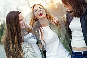 Three young women talking and laughing in the street.