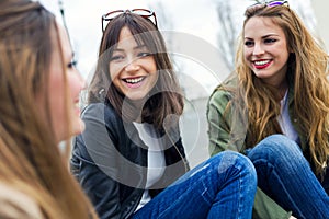 Three young women talking and laughing in the street.