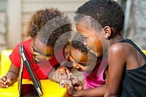 Threesome african kids having fun with tablet.
