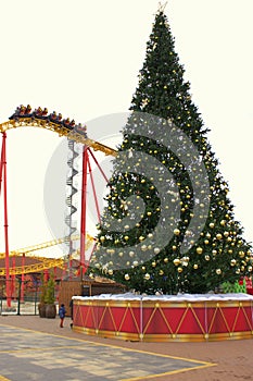Thrill lovers ride a roller coaster on the background of a Christmas tree. Christmas holidays