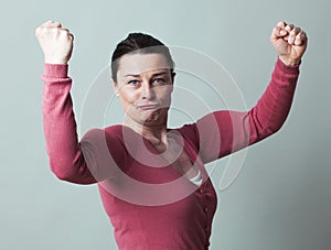 Thrilled beautiful 40s woman flexing her muscles up