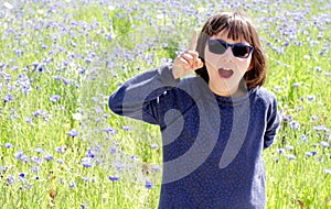 Thrilled expressive child with sunglasses over sunny cornflower meadow, outdoor photo