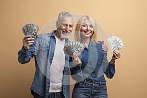 Thrilled positive elderly couple enjoying their prize, holding cash