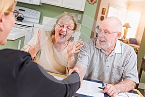 Thrilled Senior Adult Couple Celebrating Over Documents in Their Home with Agent At Signing