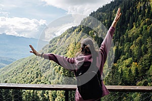 Thrilled woman enjoying the view of a mountain slope covered with forest