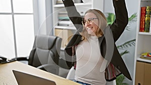 Thrilled young blonde business woman savors success as she playfully throws papers in the office, enjoying her work