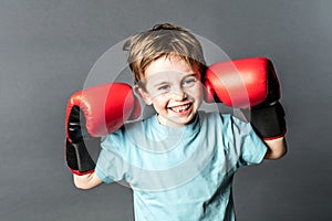 Thrilled young boy giggling with boxing gloves up for fight photo