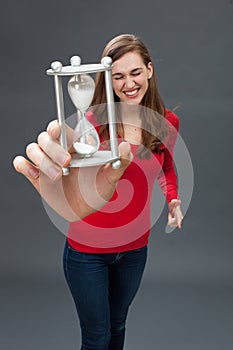 Thrilled young woman with an hour glass in oversized hand photo