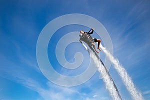 Thrillseeker, athlete strapped to Jet Lev, levitation soars into a blue sky with whispy clouds