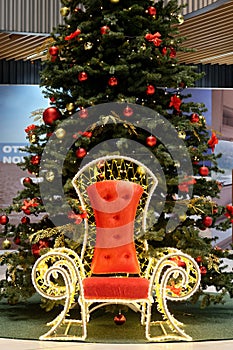 Throne for Santa Claus under the Christmas tree. Colorful balls garland glowing lamps and red berries on the branches are