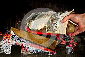 Throw birch firewood into a home fireplace. Make house warmer
