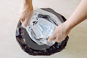 Throwing away single use medical face mask. Packing it in one time plastic bag before throwing it in trash.