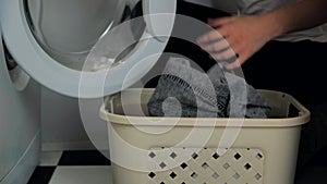 Throwing dirty laundry inside laundry basket near washing machine