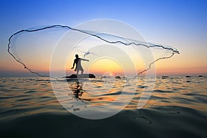 Throwing fishing net during sunrise
