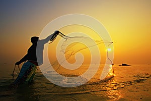 Throwing fishing net during sunset