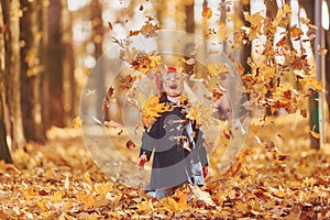 Throwing leaves into the air. Cute positive little girl have fun in the autumn park