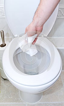 Throwing toilet tissue down into the toilet