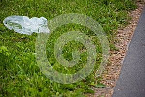 Thrown white bag on the curb with green grass