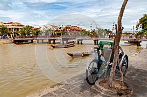 Thu Bon riverbank in Hoi An, Vietnam, with tricycle in the foreground in the daytime