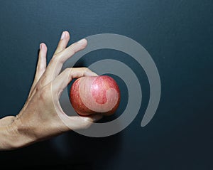 The thumb and forefinger catch apple with dark background