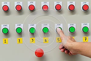 Thumb touch on green start button and red emergency stop switch