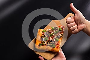 Thumb up for pizza. Piece of pizzza on wooden board. Thumb up for vegan pizza