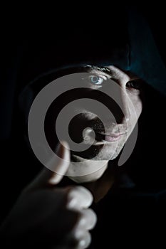 Thumb up - Portrait of a young hooded man who in the shade makes a sign of approval with his hand
