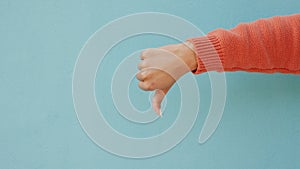 Thumbs down, dislike hand emoji or vote sign mockup on studio or blue wall background. Woman finger with bad news, fail