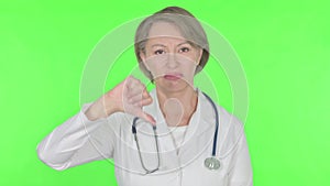 Thumbs Down by Old Female Doctor on Green Background
